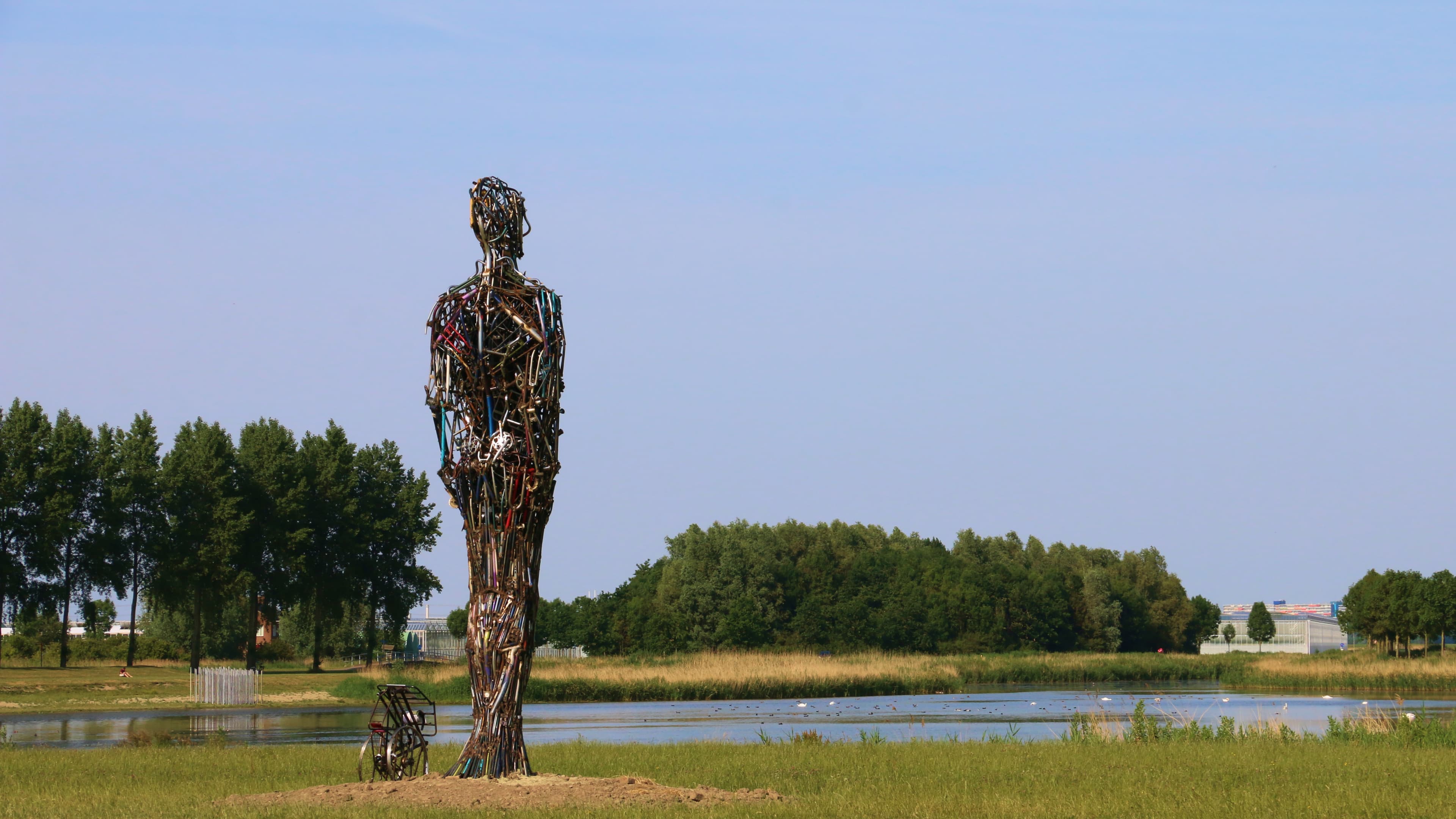 Stambeeld gemaakt van oud metaal, in de vorm van een man die over het landschap uitkijkt.