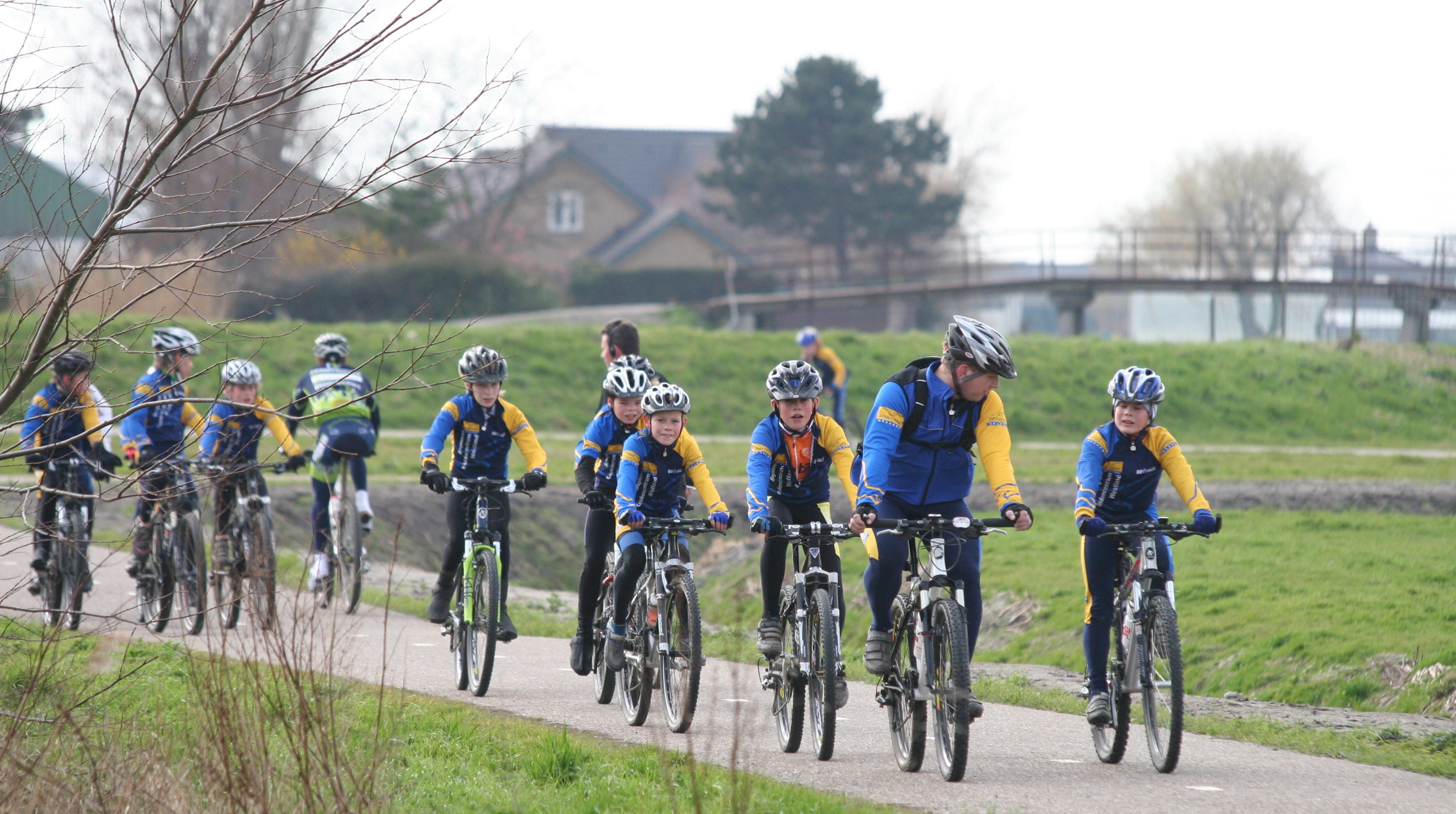 Een groep kinderen op mountainbikes, met een volwassen begeleider.